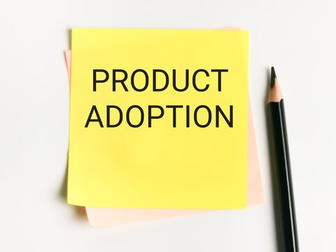 Phrase product adoption written on sticky note with a pencil.