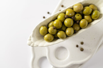 green olives in decorative dishes on a white background, top view close-up