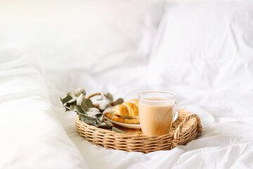 Breakfast in bed with croissant and coffee on tray