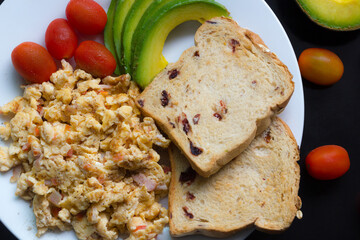 Breakfast dish with omet, bread, tomato and avocado sliced.