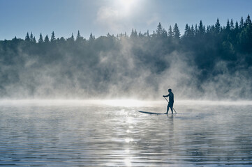Man paddling on a surf board in fog