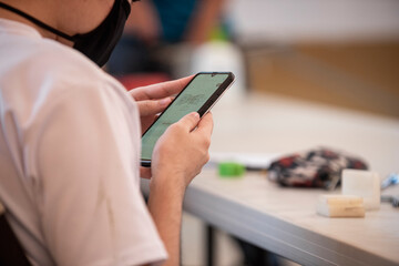 Alumno en clase con un celular leyendo información