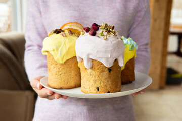 A woman holds a traditional Easter cake on the table.