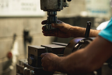 Mano de una persona con un taladro de mesa en un taller de precisión 