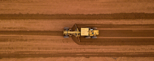 Aerial view yellow excavator building a highway, Road grader heavy earth moving, Bulldozer working at road construction. - obrazy, fototapety, plakaty