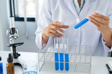 scientists researching in laboratory in white lab coat, gloves analysing, looking at test tubes sample, biotechnology concept