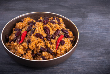 Portion of mexican tomato rice with beans in a plate on a dark background, copy space