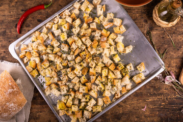 Homemade rosemary croutons, diced bread with olive oil, garlic and rosemary on a baking sheet, top view