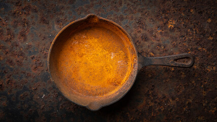 rusty cast iron skillet on a dirty rust metal plate texture background in full HD ratio, top view