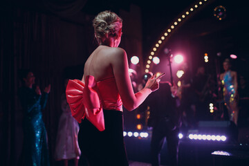 Beautiful party dress with big pink satin bow on woman in night club.