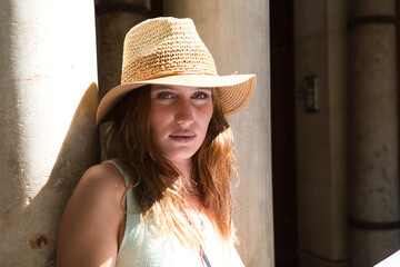 Young and pretty girl with red hair is looking at the map of the city. The girl is wearing a hat and carrying a camera. Travel and holiday concept.