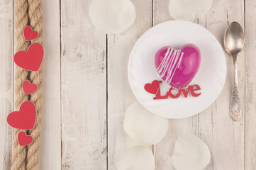 word love and white petals rose with red cake in the shape of a heart is on the table. Romantic date.