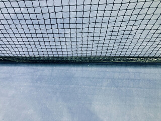 black nylon tennis net and light blue court in a half-half frame, used for background