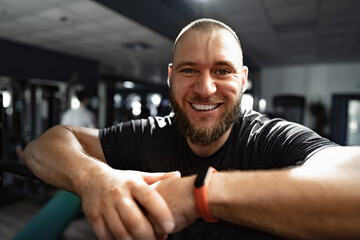 Cheerful smiling man bodybuilder standing in a gym