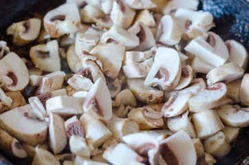 Close-up of raw mushrooms in a heated frying pan. Moisture evapo