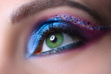 Look of green female eyes with beautiful blue shades and black eyeliner closeup
