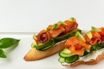 Bruschetta with red fish and fresh cucumber on a plate. Appetizing starter. White background. Space for text.