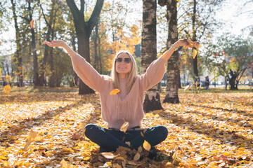 Attractive young woman smiling and throwing leaves up in the air