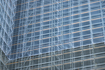 Scaffolding and metallic equipment around a high-rise building construction. No people, day light, outdoors.