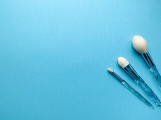 Brushes a flat lay with copy space. Beauty cosmetic makeup product layout. Stylish design. Creative fashionable concept. Cosmetics make-up brushes collection on a blue background, top view.
