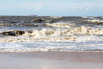 Wellen an der Nordsee mit einem Tanker im Hintergrund