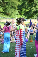 The girls in clown costumes have a performance in front of a large number of people in the park, on...
