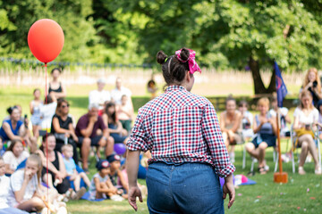 The girls in clown costumes have a performance in front of a large number of people in the park, on...