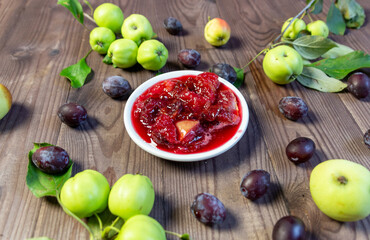 apple and plum jam made of fresh fruits and berries in plate on wooden table