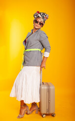 Traveler tourist woman wearing summer clothes hat hold yellow suitcase, glasses isolated on yellow background. The passenger travels abroad for the weekend. Air travel concept 

