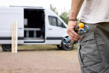 Tools held by a hand with a van in the background