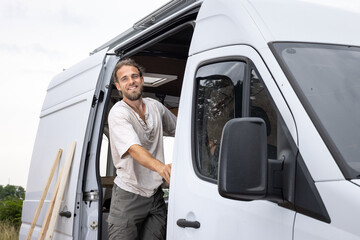 Smiling man standing in the doorway of a van
