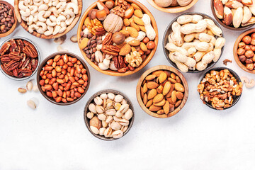 Nuts in bowls. Almonds, hazelnuts, walnuts and other. Healthy food snack mix on white table, top...