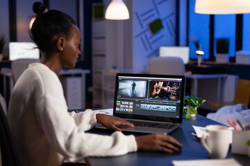 African american video editor working late at night at digital movie project editing audio film...