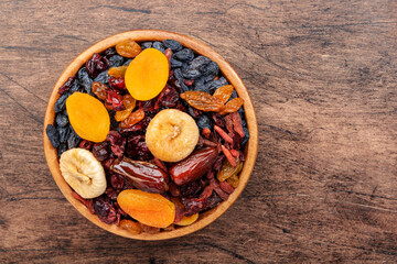 Dried fruits bowl. Healthy food snack: sun dried organic mix of apricots, figs, raisins, dates and other on wooden table, top view