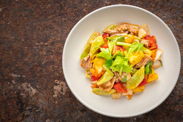 Moo Pud Preaw Wan, Thai food, sweet and sour sauce stir fried with pork, pineapple, tomato, cucumber, onion topped with celery in ceramic plate on rusty texture background, top view
