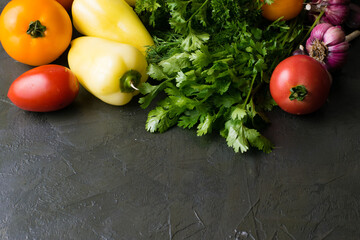 Green vegetables, broccoli, peppers, tomatoes and garlic on a dark background, top view and copy space.