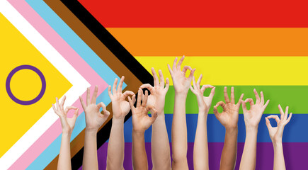 lgbtq, trans and intersex rights concept - multiracial human hands showing ok sign over rainbow...