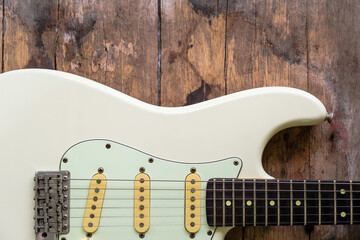 Detail of White Electric Guitar on a wood background.