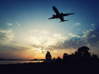 Fototapeta na wymiar Spectacular landing during the sunset in the lagoon. Wonderful sunset with an airplane landing at low altitude. Aircraft silhouette.