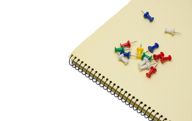 Different colored paper push pins on notepad with white copy space