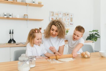 happy family in the kitchen. mother and children preparing the dough, bake cookies