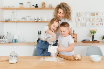 happy family in the kitchen. mother and children preparing the dough, bake cookies
