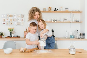 An attractive smiling family of mother, and two children, boy, girl, son, daughter cookies in a kitchen at home