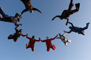 Skydiving.  A team of skydivers is in the sky.