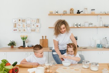 Family learning new recipe together. Happy mom and kids mixing ingredients for homemade cake, pie or cookie dough in the kitchen.