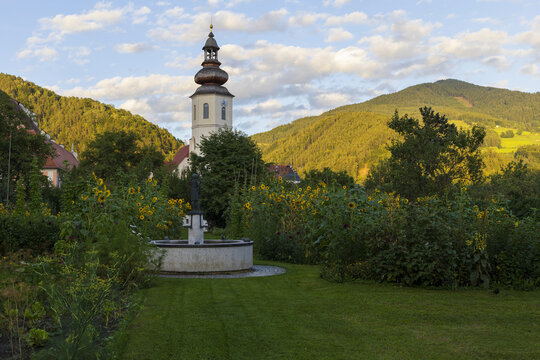 Sunset in small abbey garden with bell tower, surrounded by Alps mountains in Steiermark, south Austria