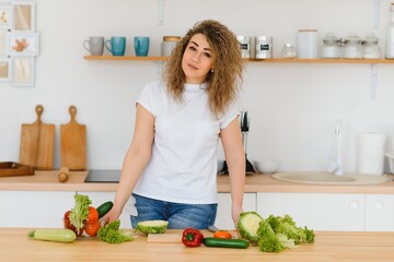 Woman making salad in kitchen. Healthy eating lifestyle concept with beautiful young woman cooking in her kitchen.