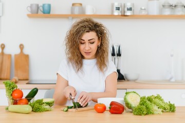Obraz na płótnie Canvas Happy young housewife mixing vegetable salad