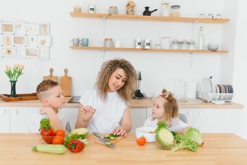 Young mother and her two kids making vegetable salad