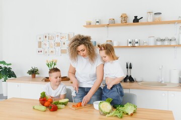 Family in a kitchen. Beautiful mother with children. Lady in white blouse.
